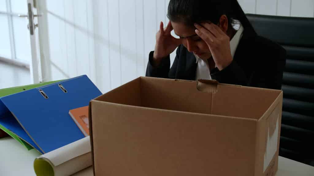 A stressed young businesswoman looking into an empty box after being fired, representing wrongful termination in Alberta