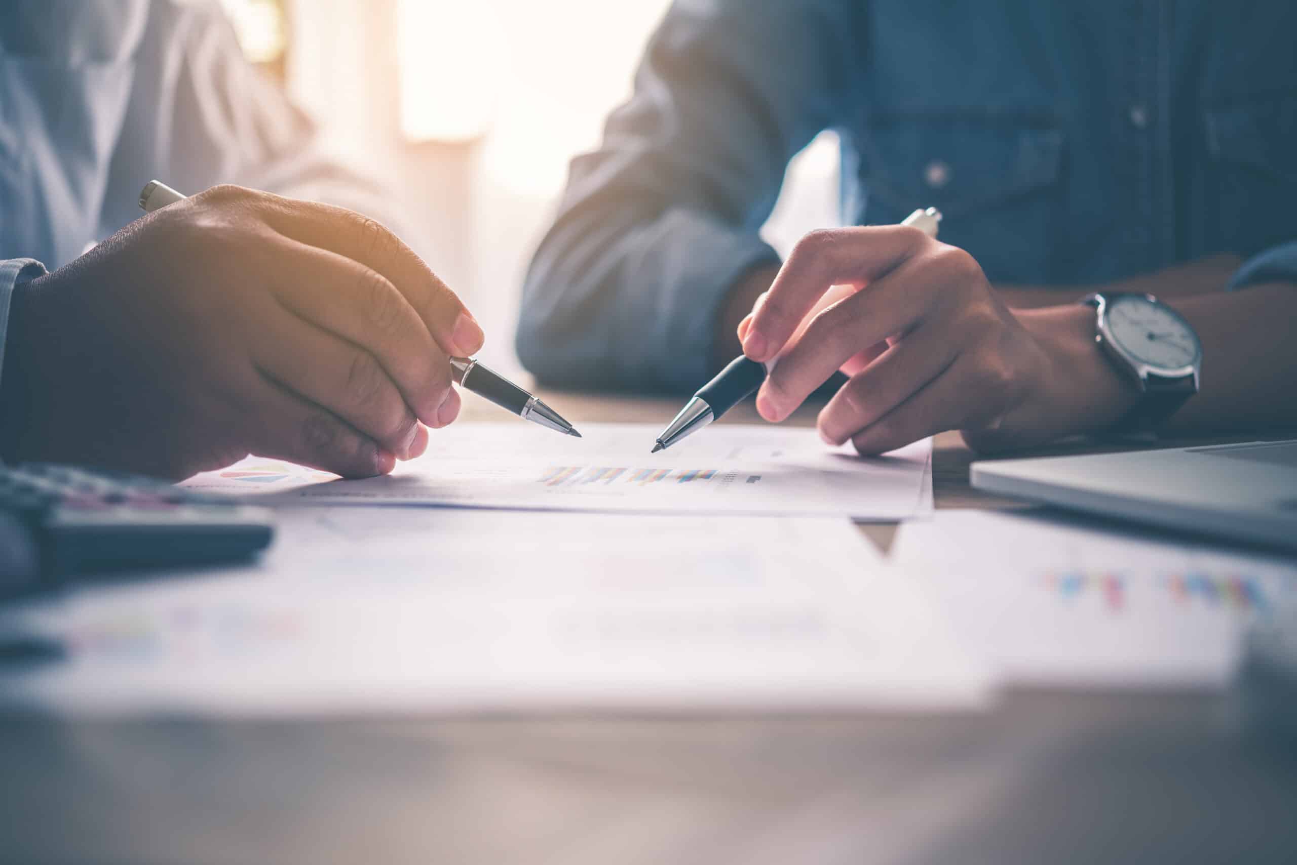 Close-up view of two people holding pens and reviewing a document, representing Civil Litigation services in Calgary and Strathmore, Alberta.