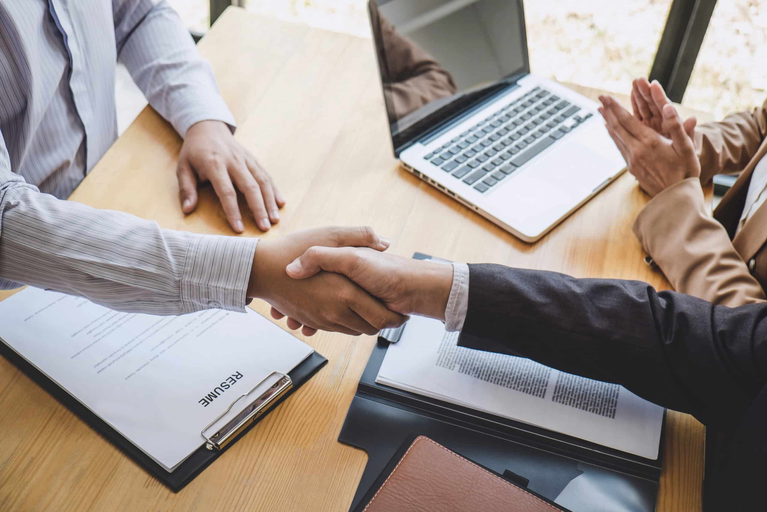 Close-up of colleages shaking hands over a desk, representing Employment Standards Law in Calgary, Alberta.
