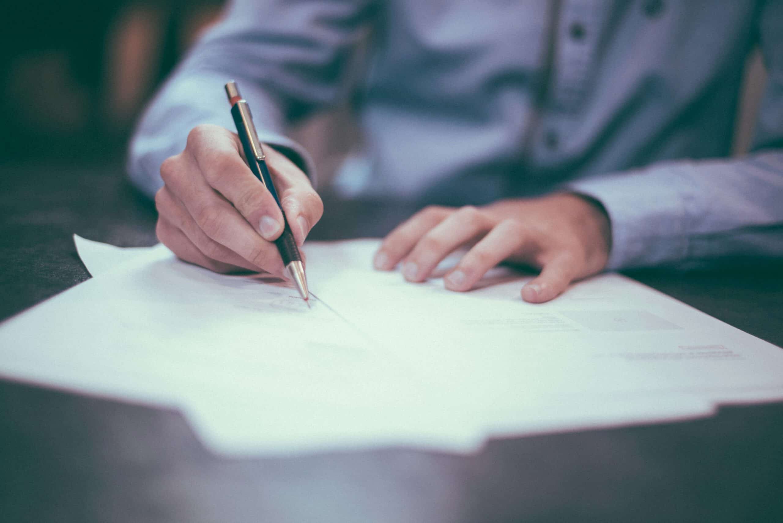 Close-up view of a person signing a contract with a pen, representing oil and gas Master Service Agreements in Calgary and Strathmore, Alberta.