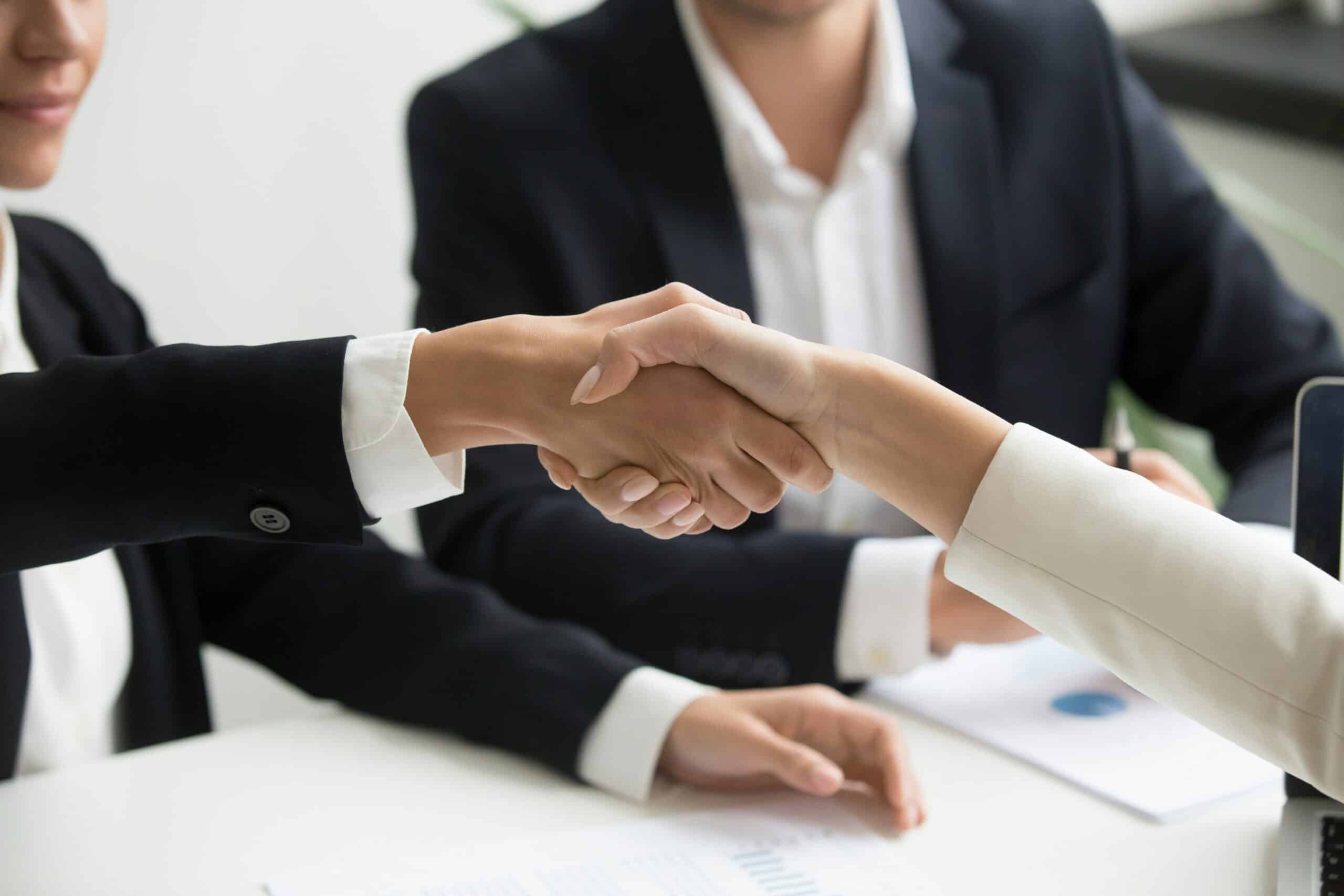 Close-up of people shaking hands over a desk, representing family law Separation Agreements in Calgary and Strathmore, Alberta.