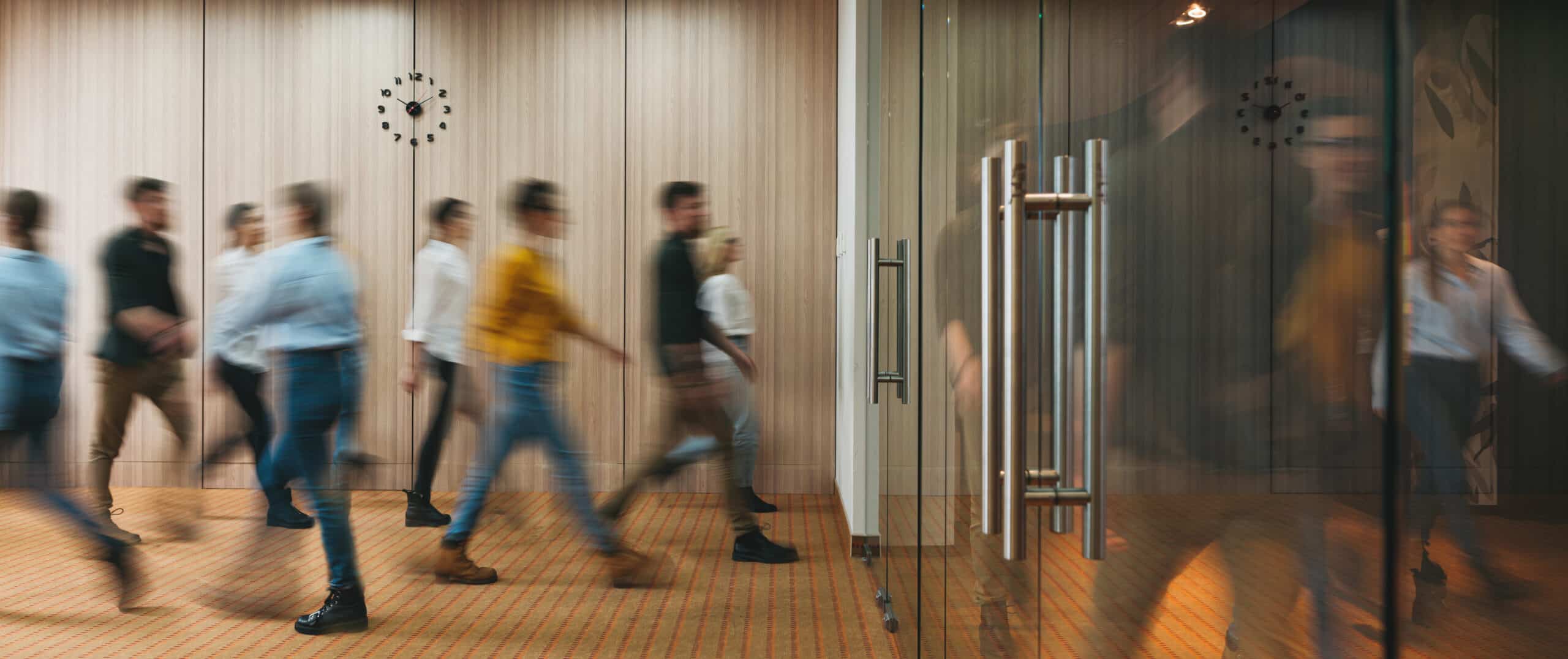 Group of employees walking through an office toward a glass door, representing Legal Services for Employees in Calgary, Alberta.