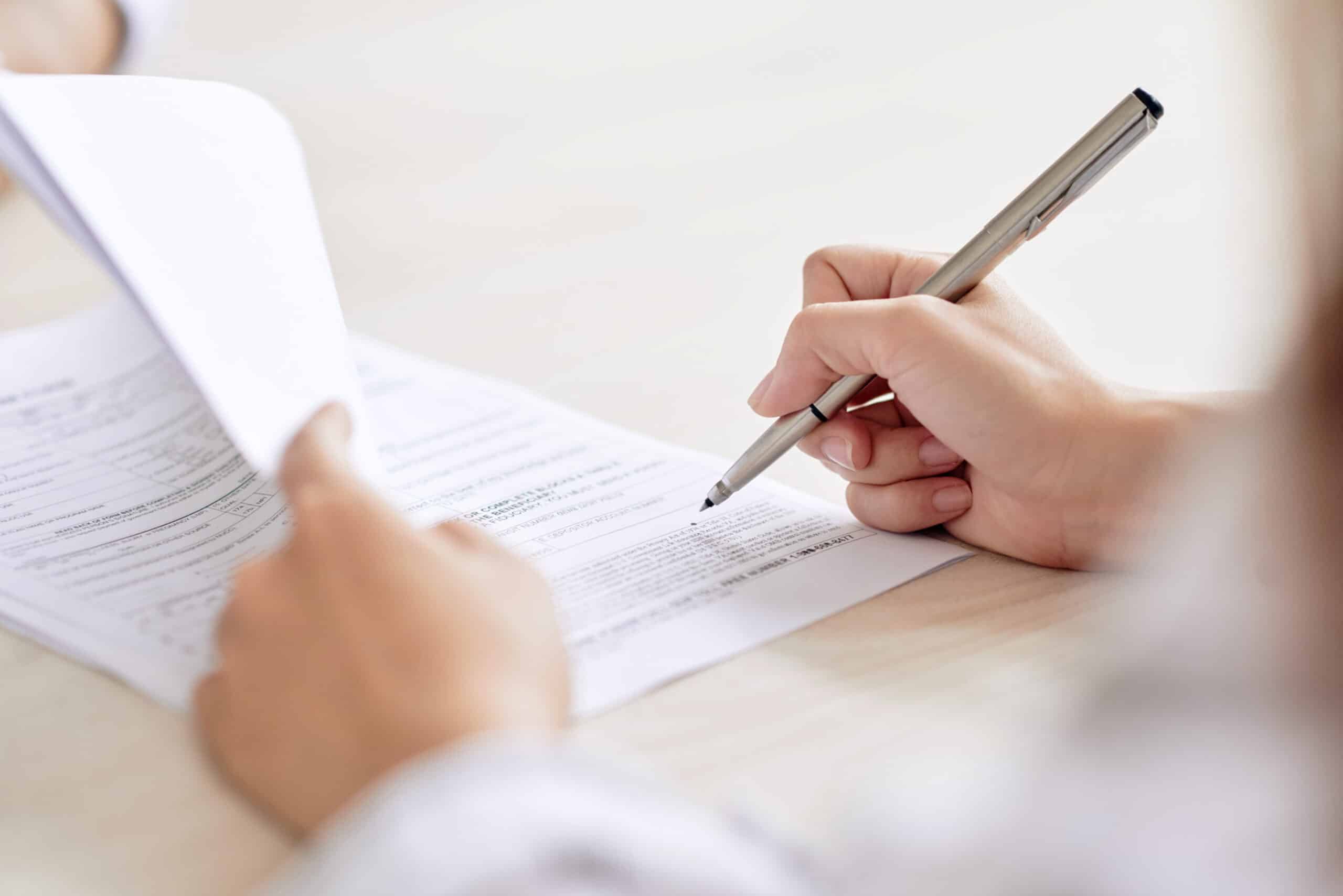 Close-up view of a person's hands reviewing and signing a contract, representing Severance Package Reviews in Calgary, Alberta.
