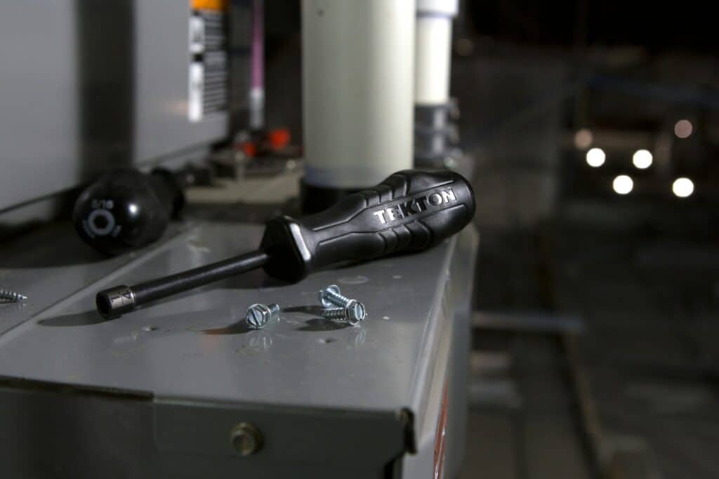 A black screwdriver with four screws scattered around it on top of an electrical box, representing wrongful dismissal damages.