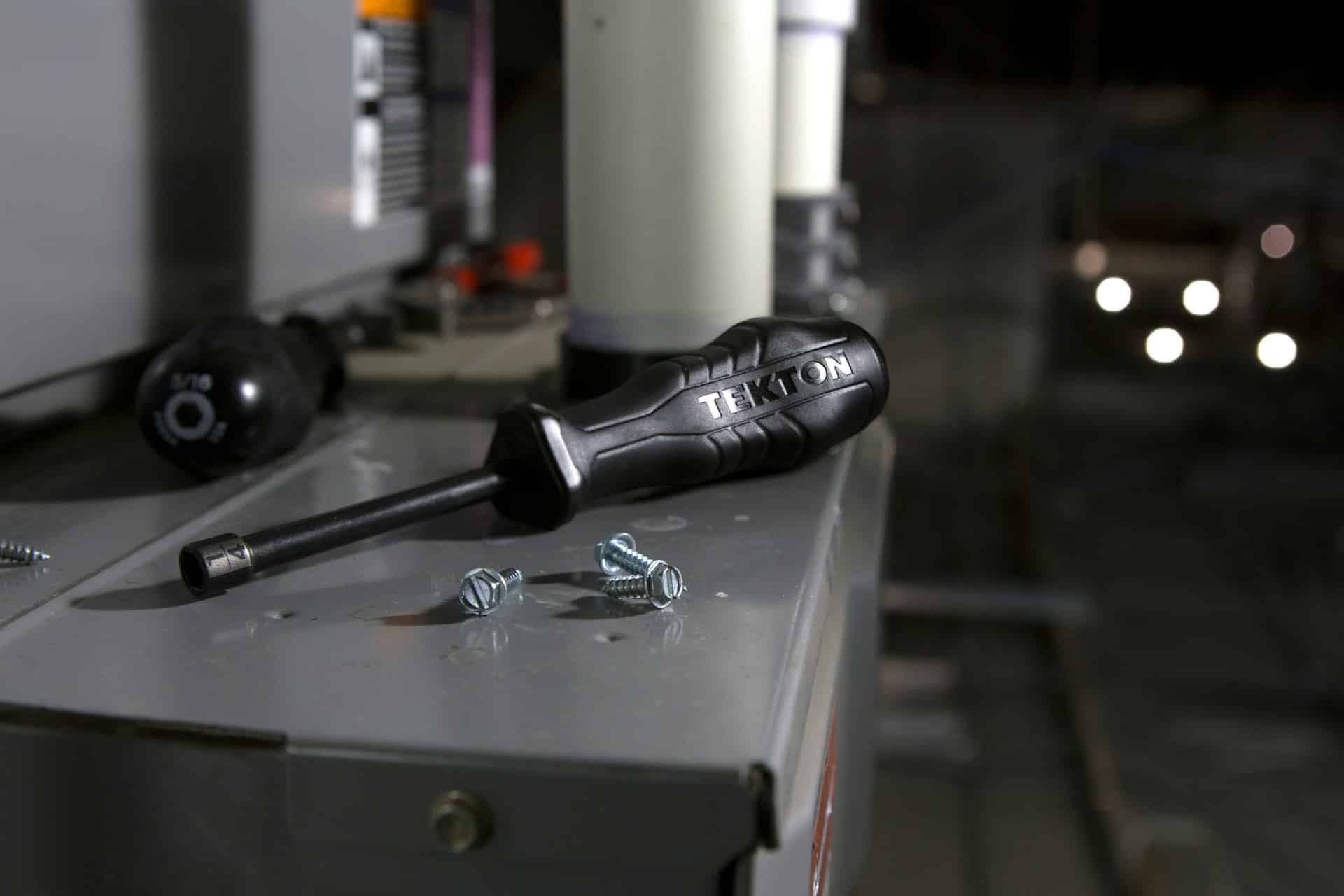 A black screwdriver with four screws scattered around it on top of an electrical box, representing wrongful dismissal damages.